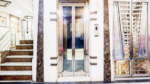 An elevator entrance with a glass door, a metal staircase to the left, and a metal gate to the right.