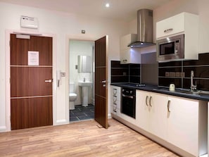 A modern kitchen with a microwave, oven, and a large range hood. - Student Only 134 New Walk (Leicester)