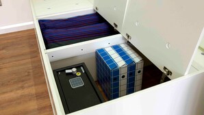 Ein Zimmer mit einem Bett, einem kleinen Tisch und einem Stauraum.