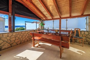 Una mesa de madera con bancos, un muro de piedra y vistas al mar.