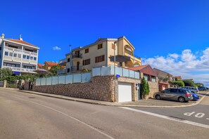 Un edificio de varios pisos con fachada de piedra, un garaje y un coche estacionado.