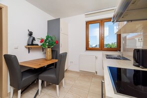 A compact kitchen with a dining table, chairs, a coffee maker, and a view through the window. - Cozy vacation apartment with pool and terrace in Crikvenica (Crikvenica)