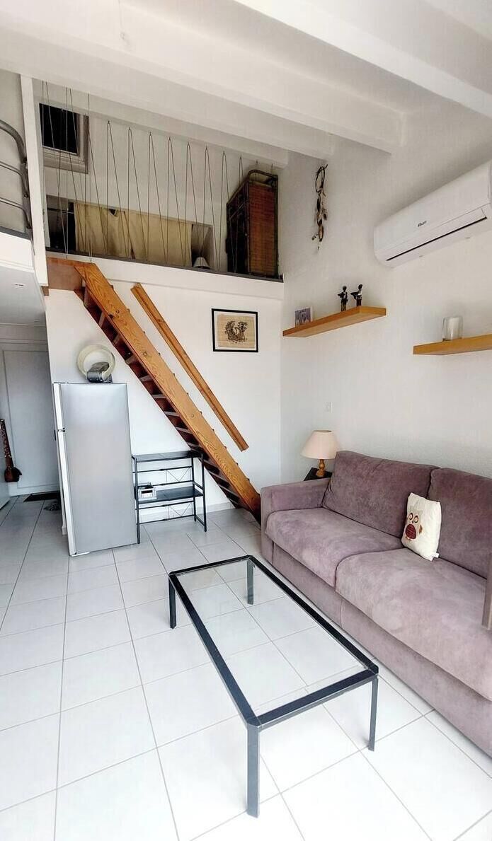 A living room with a staircase, a sofa, a coffee table, and a refrigerator.