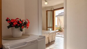 Habitación con lavadora blanca Hisense, una planta de flor roja en maceta y vistas a un balcón exterior con mesa y sillas.