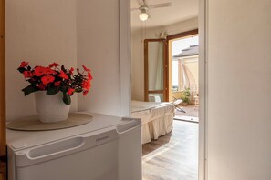 Una stanza con una lavatrice Hisense bianca, una pianta in vaso con un fiore rosso e vista su un balcone esterno con tavolo e sedie.
