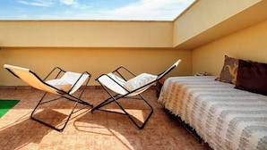 Una habitación con una cama, dos sillones y vista al cielo.