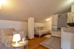 Un dormitorio con cama, mesita de noche, lámpara y una pequeña mesa con una taza.