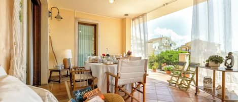 A balcony with a table set for dining, a wicker basket with books, and a view of buildings.