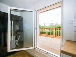 Una habitación con puerta de vidrio corrediza que da a una terraza exterior con barandal de madera.