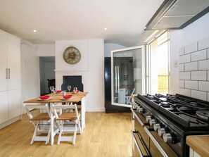 Una cocina moderna con una mesa de comedor, sillas, estufa y un reloj de pared.