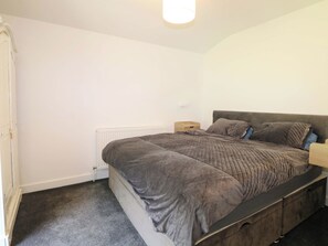 A bedroom with a bed, bedside tables, a radiator, and a wardrobe. - Woodside (Battle)