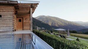 Eine Holzhütte mit einem Glas-Endlospool, einer Tür und Blick auf Berge.