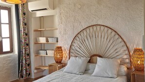 Un dormitorio con una cama grande, cabecera de madera, mesitas de noche con lámparas, un armario y una ventana con cortinas.