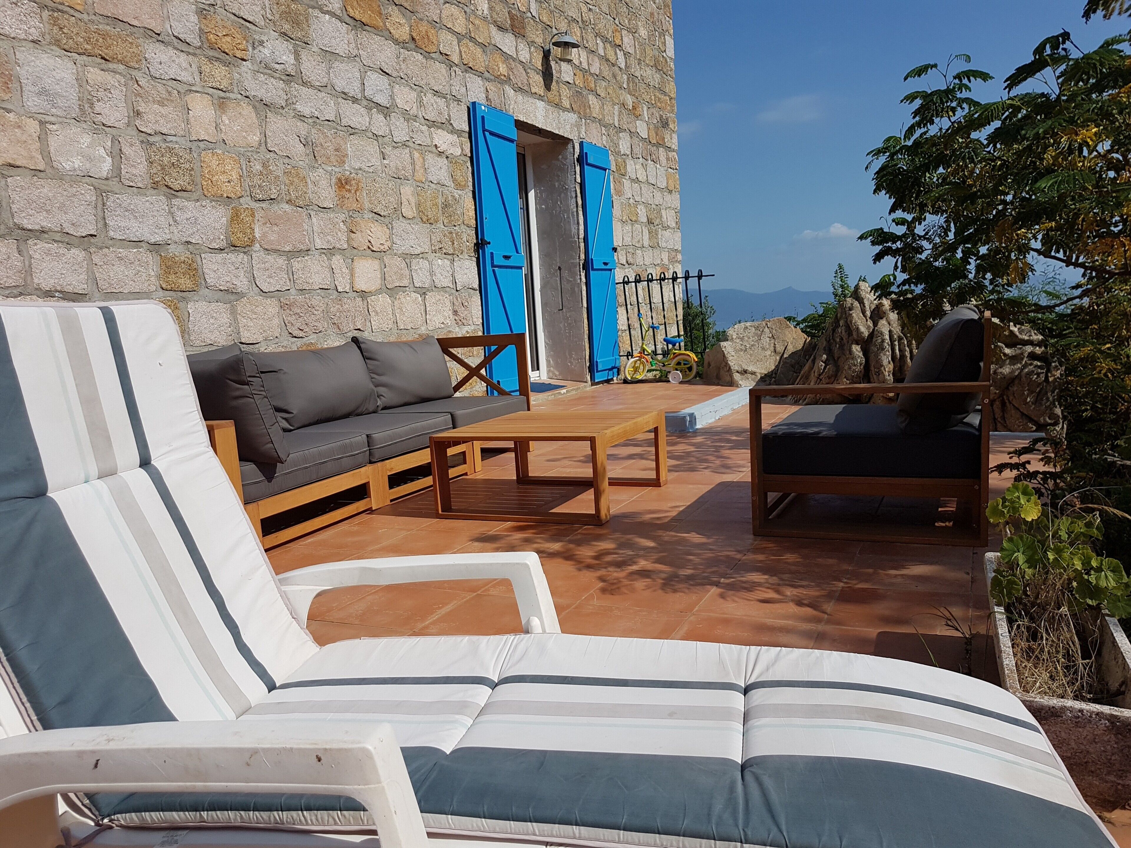 A stone building with a terrace, a sofa, a chair, and a table.