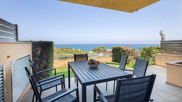 Eine Terrasse mit Tisch, Stühlen, einer Obstschale und Blick auf das Meer.