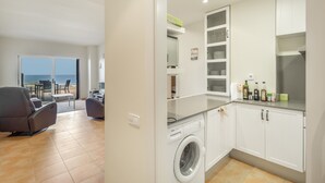 Eine moderne Küche mit Waschmaschine, ein Essbereich mit Blick und ein Balkon mit Gartenmöbeln.