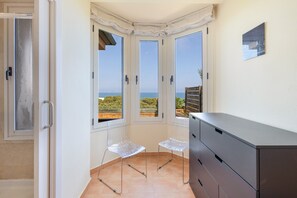 A room with a view of the sea, a cabinet, and two chairs. - Apartment 'Sa Calma I Bajos D' with Sea View, Wi-Fi and Air Conditioning (Begur)