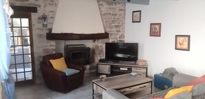 Ein Wohnzimmer mit Steinwand, Kamin, Fernseher, Ledersessel und Sofa.