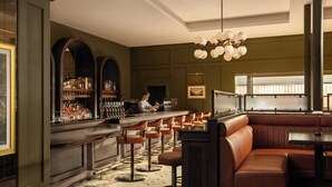 A bar area with a bartender, bar stools, a counter with bottles, and a large window. - The Grace Wesport Estate  (Westport)
