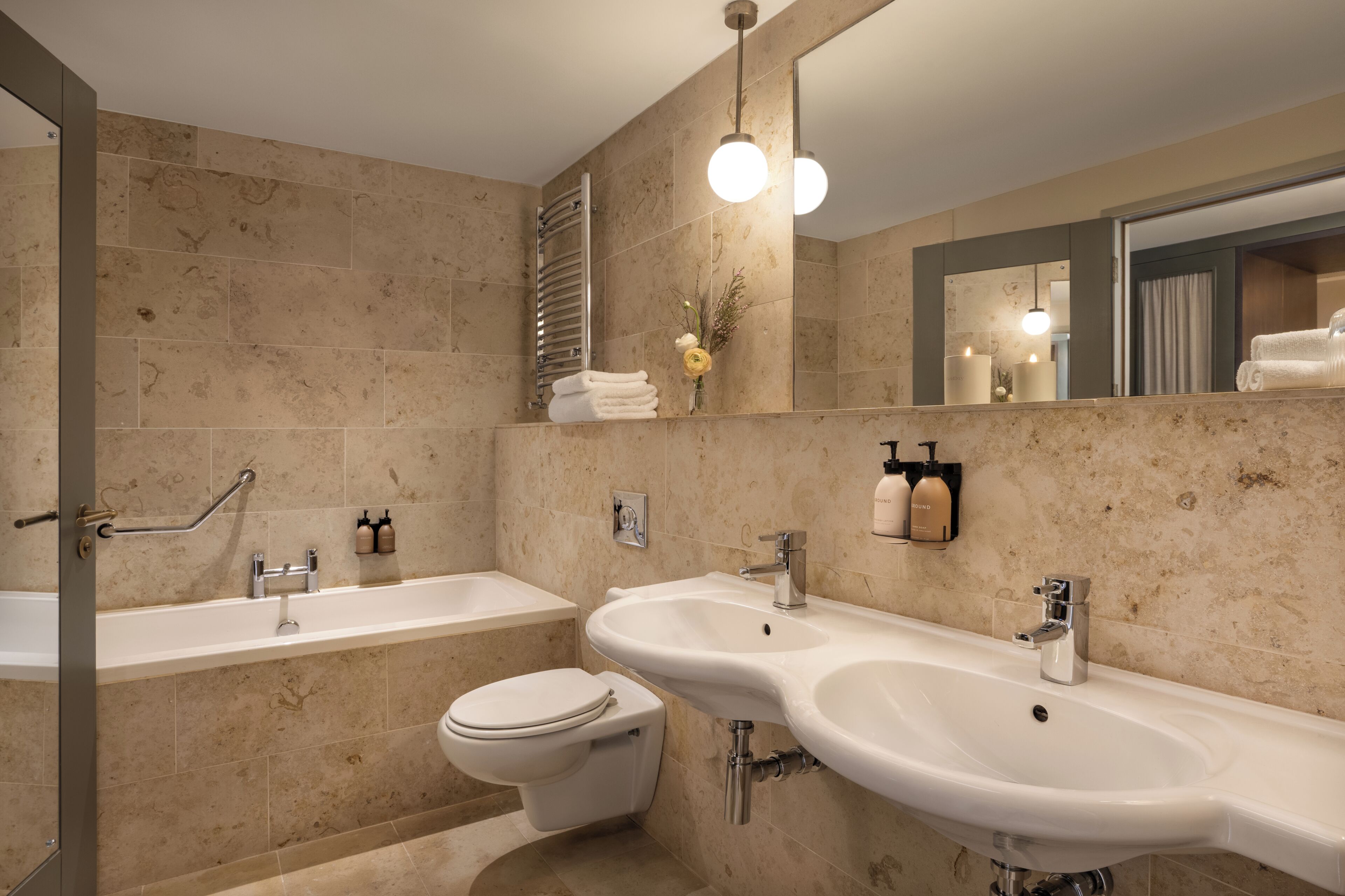 A modern bathroom with a bathtub, two sinks, a toilet, and a shower.