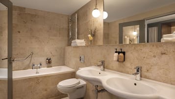 Une salle de bain moderne équipée d’une baignoire, de deux lavabos, de toilettes et d’une douche.