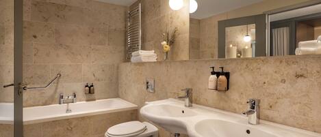 Un baño moderno con bañera, dos lavamanos, inodoro y ducha.