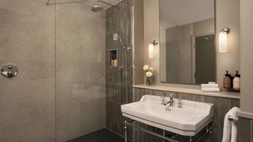 Een moderne badkamer met een douchecabine van glas, een witte wastafel en een grote spiegel.