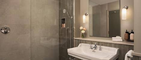A modern bathroom with a glass-enclosed shower, a white sink, and a large mirror.