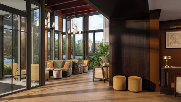 A spacious room with large windows, a wooden floor, and a seating area with sofas and ottomans. - The Grace Wesport Estate  (Westport)