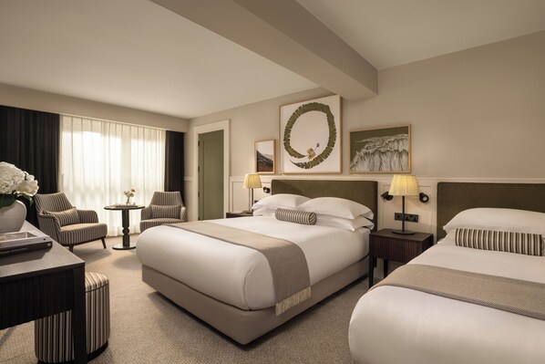 A hotel room with a large bed, two armchairs, a small table, and a nightstand with lamps. - The Grace Wesport Estate  (Westport)