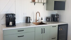 A modern kitchen with a coffee maker, kettle, toaster, and microwave.