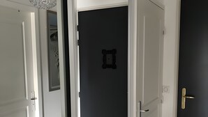 Käytävä, jossa on valkoinen ovi, musta ovi ja ovi, jossa on koristeellinen kehys.
