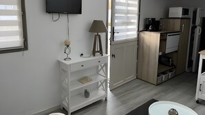 Una cucina compatta con TV, lampada e mobiletto.