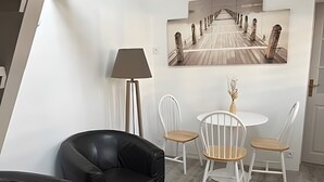Una camera moderna con un divano in pelle nera, un tavolo bianco rotondo con un oggetto decorativo, una lampada e un quadro raffigurante un ponte.