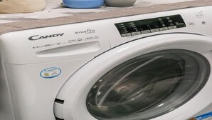 A Candy SmartPro Inverter washing machine with a digital display, control panel, and a front-loading door. - Adorable 1-bedroom apartment with AC in charming Roma (Roma)