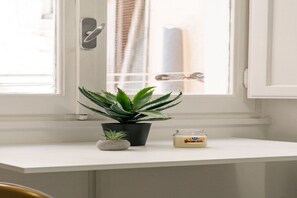 Ein weißer Fensterbrett mit einem Topf mit Aloe Vera, einem kleinen Stein und einer Honiggläser.