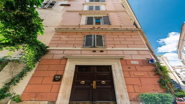 A building with a dark brown double door, a small balcony with a potted plant, and a number '57' sign above the door. - Adorable 1-bedroom apartment with AC in charming Roma (Roma)