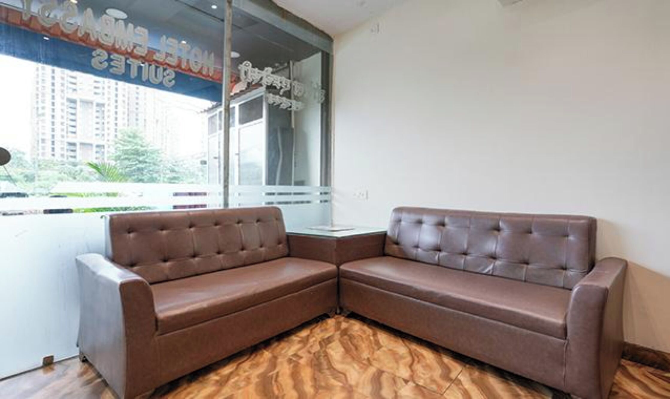 A corner seating area with a brown sofa and a glass partition.
