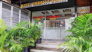 A hotel entrance with a sign reading 'HOTEL EMBASSY SUITES' and a visible window displaying rooms. - Via Embassy Suites (Mumbai)