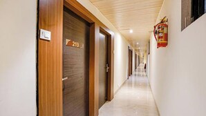 A corridor with wooden doors, a fire extinguisher on the wall, and a number sign on the door. - Via Embassy Suites (Mumbai)