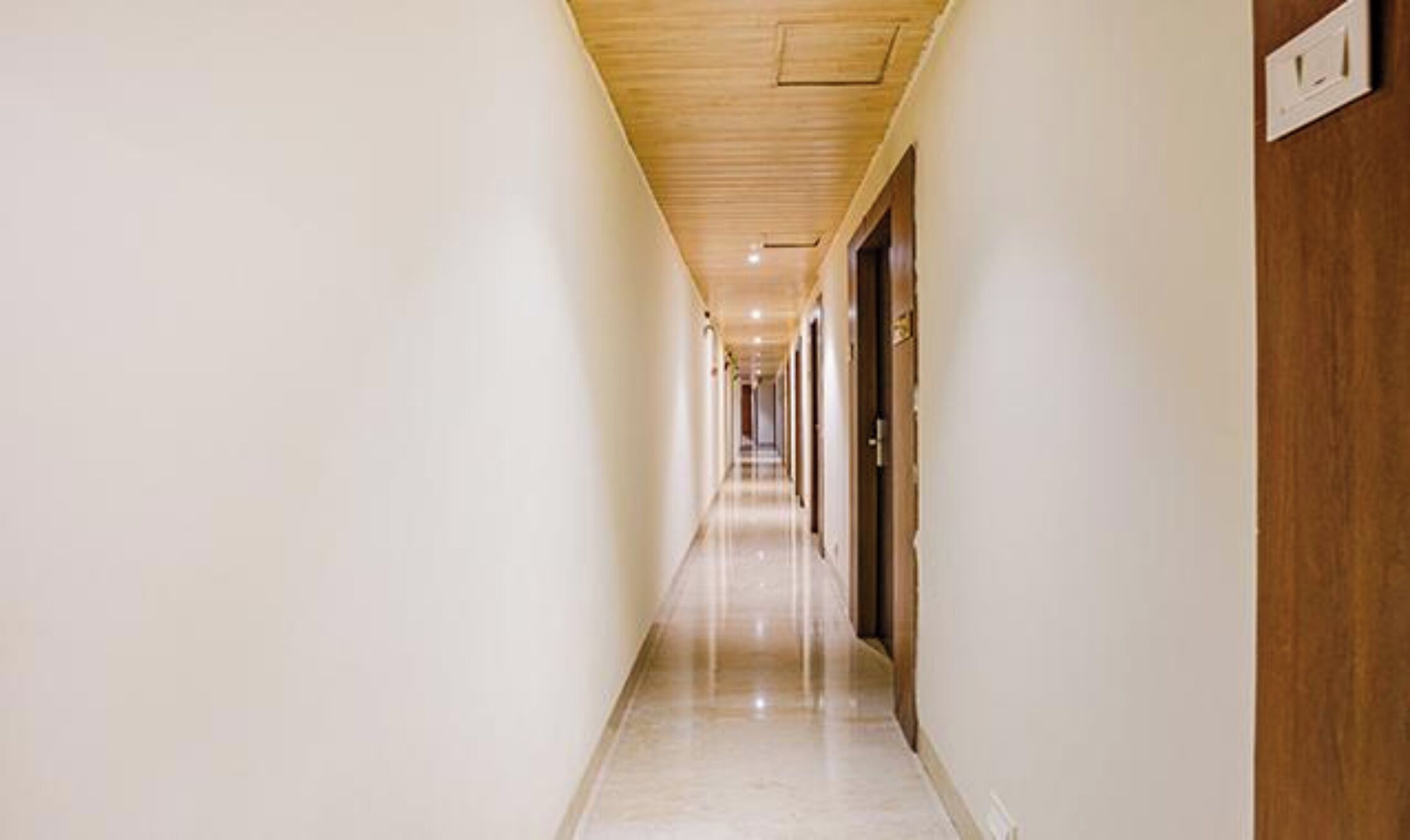 A long, narrow hallway with a wooden ceiling and white walls.