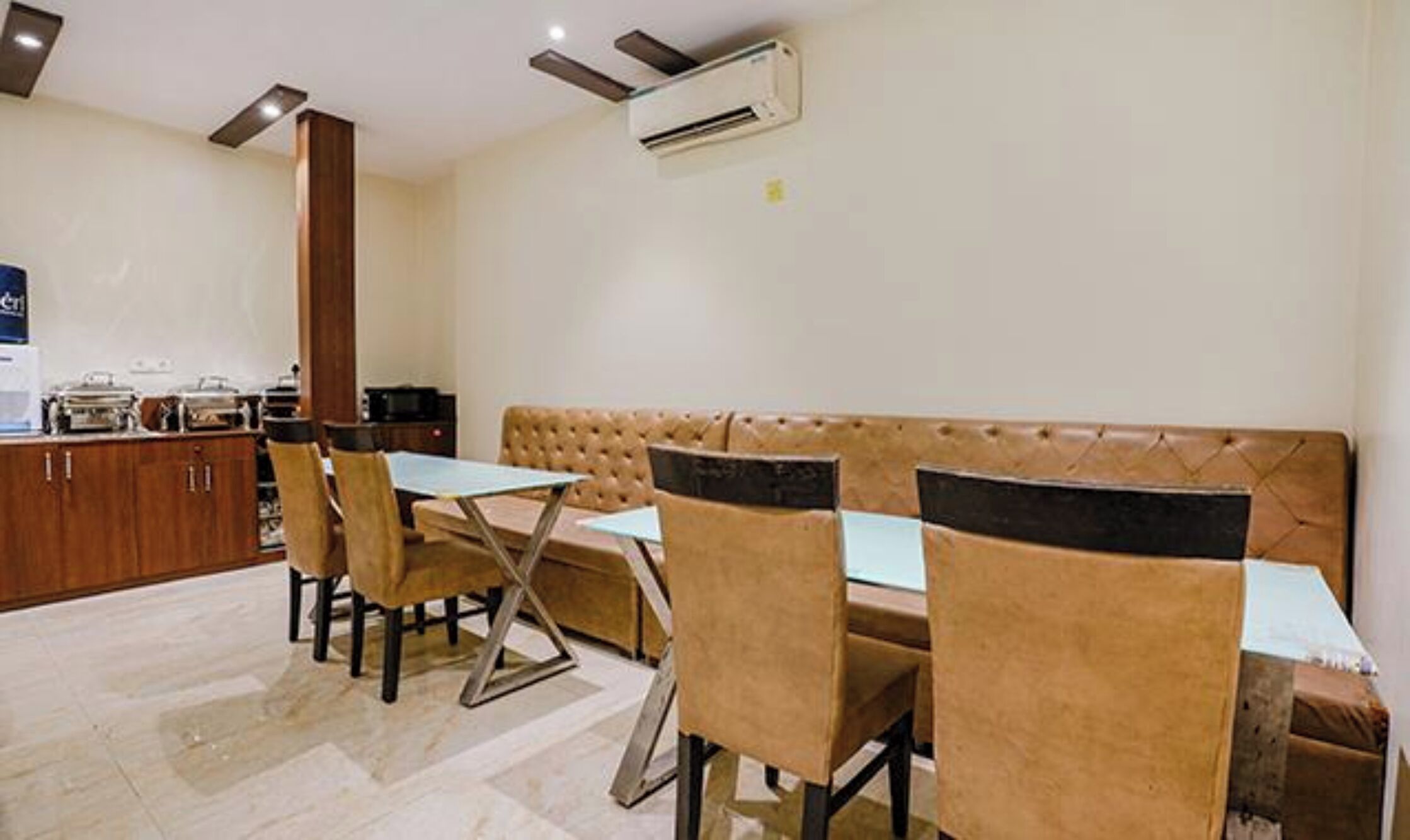 A dining area with a table, chairs, a sofa, and an air conditioning unit.