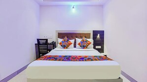 A bedroom with a bed, two pillows, a nightstand, and a wall-mounted lamp. - Via Embassy Suites (Mumbai)