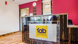 A reception desk with a clock, a sign for 'fab hotels,' and a wooden floor. - Via Embassy Suites (Mumbai)