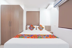 A bedroom with a bed, a wardrobe, a headboard, and a window with blinds. - FabHotel Galaxy Apartment (Pune)