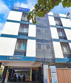 A multi-story building with a sign for 'fab hotels' and a sign in a local language. - Via Galaxy Apartments (Pune)
