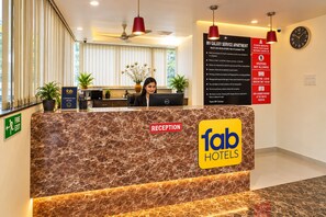 A reception desk at Fab Hotels with a marble counter, a reception sign, and a sign detailing MV Galaxy Service Apartment rules. - FabHotel Galaxy Apartment (Pune)