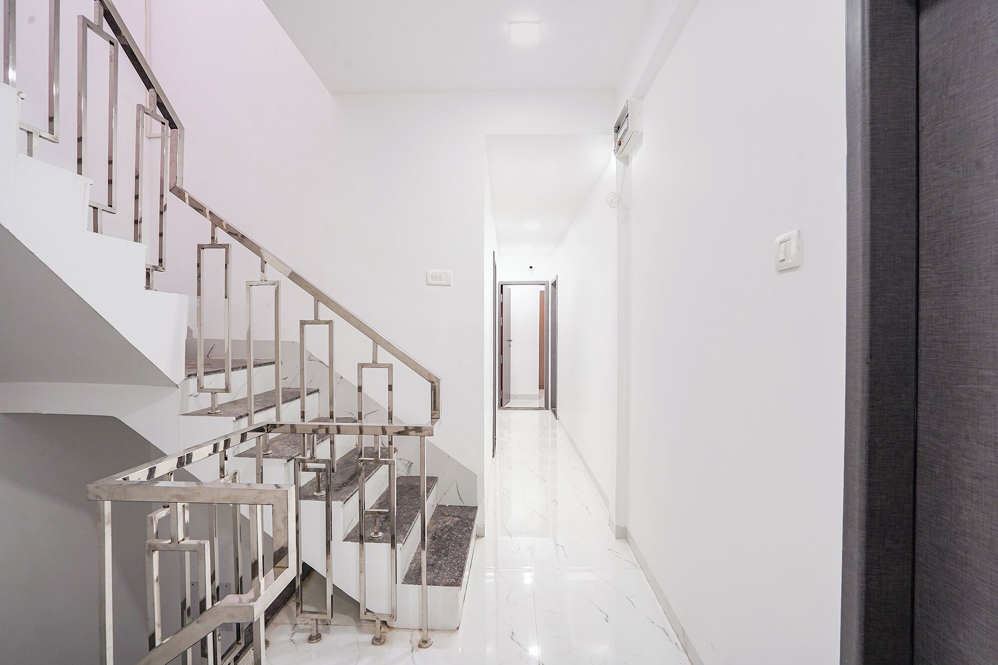 A modern interior with a staircase, a hallway, and a door leading to another room.