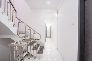 A modern interior with a staircase, a hallway, and a door leading to another room. - FabHotel Galaxy Apartment (Pune)