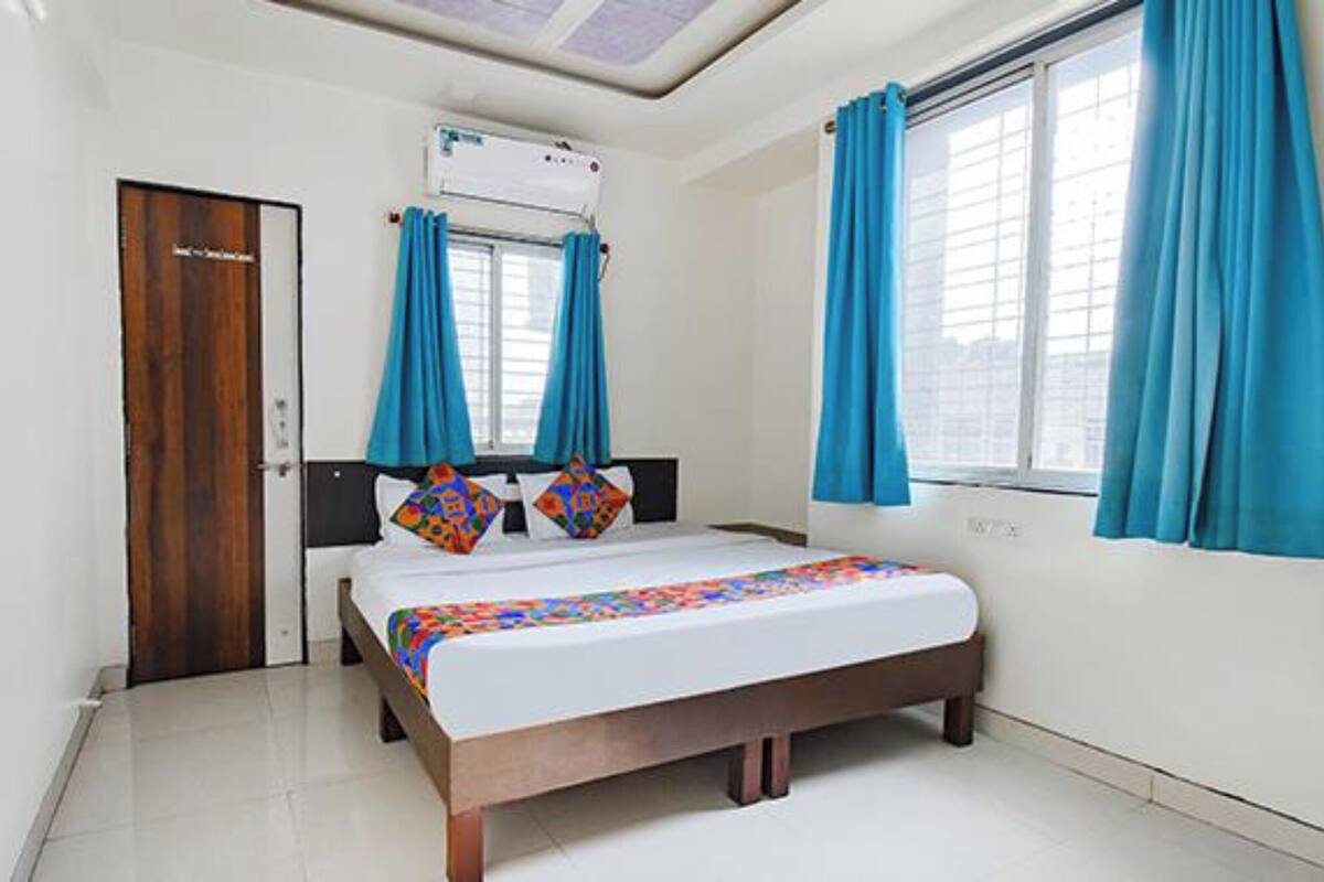 Un dormitorio con cama, una puerta y una ventana con cortinas.